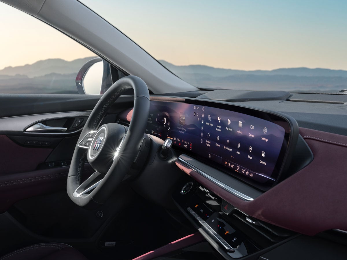 Interior of a modern car with a digital dashboard and large infotainment screen, overlooking a mountain landscape.